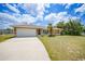 Charming single-story home with a well-manicured lawn, palm tree, and attached two-car garage at 657 Hartford Nw Dr, Port Charlotte, FL 33952