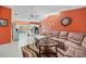 Bright living room featuring an orange accent wall, a brown couch, and sliding door access at 657 Hartford Nw Dr, Port Charlotte, FL 33952
