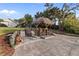 Outdoor tiki bar seating area and lounge chairs with a lush tropical landscape and brick paved patio at 719 Ellicott Nw Cir, Port Charlotte, FL 33952