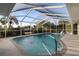 Screened-in pool area with a fountain, stainless ladder and lush surrounding landscaping at 719 Ellicott Nw Cir, Port Charlotte, FL 33952