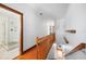 Upstairs hallway with wood floors, wood railing, and a bathroom with tiled shower at 740 W Virginia Ave, Punta Gorda, FL 33950