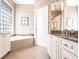 Bathroom with large tub with glass block window above, marble countertops, and diamond pattern wall coverings at 10227 Windsong Rd, Punta Gorda, FL 33955