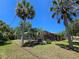 Backyard featuring a screened-in pool area surrounded by lush palm trees and greenery at 1173 Belkton Ave, Port Charlotte, FL 33948