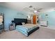 Spacious main bedroom features blue walls, a ceiling fan, a large bed, and adjoins the laundry room at 1249 Indus, Venice, FL 34293