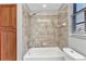 Shower over tub in neutral shades with a wood cabinet for storage and a window at 1349 Aqui Esta Dr # 121, Punta Gorda, FL 33950