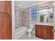Bright bathroom featuring a shower over tub, wood vanity, and natural light at 1349 Aqui Esta Dr # 121, Punta Gorda, FL 33950