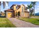 Charming two-story home with a stone facade, brick driveway, lush lawn and a three-car garage at 14142 Fort Myers Ave, Port Charlotte, FL 33981