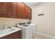Well-lit laundry room features updated washer and dryer, dark wood cabinetry, and a sink at 14142 Fort Myers Ave, Port Charlotte, FL 33981