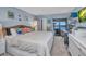Light blue bedroom featuring coastal decor, a king bed, and a desk with a view to the outside balcony and waterway at 1701 Beach Rd # 305, Englewood, FL 34223