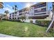 Condo building featuring balconies, lush landscaping, and convenient covered parking in a sunny, tropical setting at 1701 Beach Rd # 305, Englewood, FL 34223
