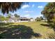 Spacious backyard with green grass, mature palms, and a screened lanai, ideal for outdoor living at 18263 Ohara Dr, Port Charlotte, FL 33948