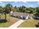 Single-story home with a well-manicured lawn, palm trees, and a long driveway in a sunny setting at 18263 Ohara Dr, Port Charlotte, FL 33948