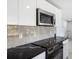 Modern kitchen features stainless steel appliances, sleek white cabinetry, and black countertops with matching backsplash at 18263 Ohara Dr, Port Charlotte, FL 33948