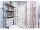 Bright bathroom featuring white shower tile, floral shower curtain, and a convenient shelving unit at 20016 Sancraft Ave, Port Charlotte, FL 33954
