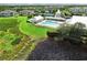 Aerial view of a community pool with chairs, lush green lawn, a lake and surrounding residential area at 2024 Royal Tern Cir, Punta Gorda, FL 33983