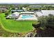 Aerial view of a community pool, clubhouse, tennis courts, lush green lawn, and lake at 2024 Royal Tern Cir, Punta Gorda, FL 33983