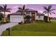 Attractive home with a manicured lawn, a two-car garage, and a welcoming entrance at dusk at 24103 Pyramid Way, Punta Gorda, FL 33955