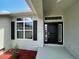 Close-up of front door and window with black shutters; enhanced by mature landscaping at 25156 Rosamond Ct, Punta Gorda, FL 33983