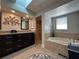 Elegant bathroom featuring a soaking tub, walk-in shower, dual vanities, and a skylight at 25263 Padre Ln, Punta Gorda, FL 33983