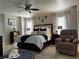 Well-lit main bedroom boasts a comfortable bed, a ceiling fan, and a cozy sitting area at 25263 Padre Ln, Punta Gorda, FL 33983