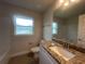 Bathroom featuring granite countertop, large mirror, window, toilet and vanity with storage, showcasing modern elegance at 26209 Madras Ct, Punta Gorda, FL 33983