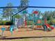 Playground with climbing structure, slide, and play stations on a wood chip ground cover at 26209 Madras Ct, Punta Gorda, FL 33983