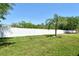 Green backyard with a tall white fence, a palm tree, and well-manicured lawn at 27854 Arrowhead Cir, Punta Gorda, FL 33982