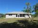 Back of house with screened-in porch, lawn, and partial view of yard with a variety of green foliage at 296 Milford St, Port Charlotte, FL 33953