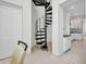 View of black spiral staircase and access to the kitchen with white cabinets and black countertops at 4213 Gardner Dr, Port Charlotte, FL 33952