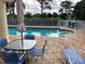 A community pool with lounge chairs and umbrella table at 5800 Sabal Trace Dr # 1302, North Port, FL 34287