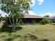 Backyard exterior of home with screened patio and mature tree at 582 Reading Nw St, Port Charlotte, FL 33952