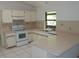 The kitchen features white appliances, countertops, and tiled flooring, with a window overlooking the backyard at 582 Reading Nw St, Port Charlotte, FL 33952