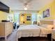 Bright bedroom with sunny yellow walls, a ceiling fan, and large window view at 582 Ridgewood Nw St, Port Charlotte, FL 33952