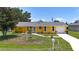 Attractive single-Gathering home featuring a bright yellow exterior, a well-maintained lawn, and a charming front yard at 582 Ridgewood Nw St, Port Charlotte, FL 33952