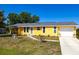 Bright yellow single-story home with attached garage, landscaped yard, and paved walkway at 582 Ridgewood Nw St, Port Charlotte, FL 33952