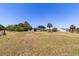 Large grassy lot with distant view of home with screened in pool and palm trees at 6308 Grove Blvd, Punta Gorda, FL 33982