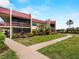 Two-story condo building featuring a red roof, landscaping, and sidewalk at 72 Boundary Blvd # 226, Rotonda West, FL 33947