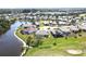 An aerial view showcases a home on the water with golf course views and lush landscaping at 10203 Windsong Rd, Punta Gorda, FL 33955