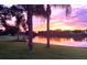 Serene pond reflecting the sunset sky, surrounded by lush landscaping at 10203 Windsong Rd, Punta Gorda, FL 33955