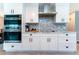 Bright white kitchen with stainless steel appliances, marble counters, and tiled backsplash at 12420 Minot Ave, Port Charlotte, FL 33981