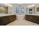 An elegant bathroom features dual vanities, a soaking tub, large mirrors, and tiled floors at 12472 Davie Ct, Venice, FL 34293