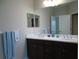 Bathroom with double vanity, framed mirror and a towel rack with blue striped towel at 12656 Sagewood Dr, Venice, FL 34293