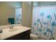 Bathroom features a vanity with a dark wood cabinet, sink, and floral shower curtain at 12656 Sagewood Dr, Venice, FL 34293