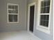 Close-up of the front porch featuring a dark front door, two windows, and neutral siding at 12656 Sagewood Dr, Venice, FL 34293