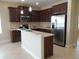 Gourmet kitchen featuring dark cabinets, quartz countertops, stainless steel appliances, and a breakfast bar at 12656 Sagewood Dr, Venice, FL 34293