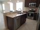 Well-lit kitchen featuring stainless steel appliances, dark cabinets and an eat-in island at 12656 Sagewood Dr, Venice, FL 34293