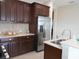 Close-up of kitchen featuring dark cabinets, stainless steel refrigerator, and breakfast bar with sink at 12656 Sagewood Dr, Venice, FL 34293