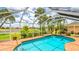 Gorgeous in-ground pool features blue tile and screen enclosure overlooking pristine landscaping and lake views at 2202 Peterborough Rd, Punta Gorda, FL 33983