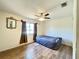 This bedroom features wood floors, a ceiling fan, a window with curtains, and a decorative mirror at 2314 Lee Ter, Port Charlotte, FL 33952