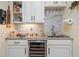 Home wet bar featuring marble countertop, custom cabinetry, modern lighting, and a wine fridge at 265 White Marsh Ln, Rotonda West, FL 33947